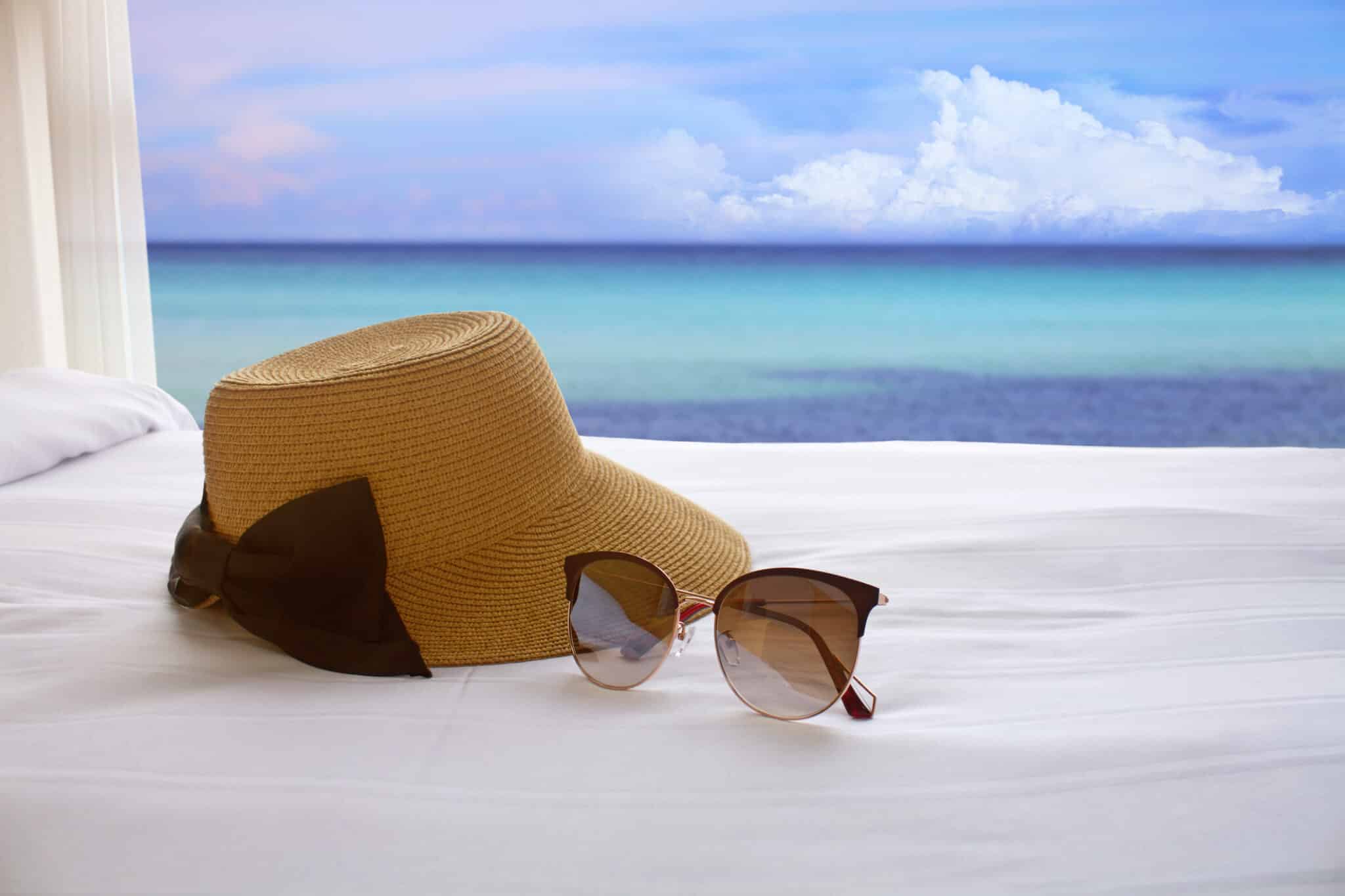 kapelusz z okularami na łóżku z widokiem na ocean